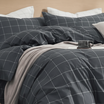A dark gray bedding set with a white windowpane grid pattern, styled on a bed with a light gray throw blanket and white pillows.