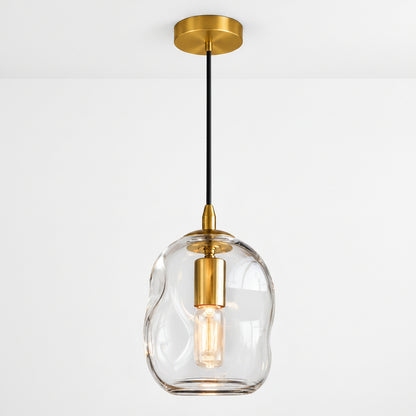 A modern pendant light with a wavy, organic-shaped clear glass shade, a brushed gold ceiling canopy and collar, and a black hanging cord with a gold accent.