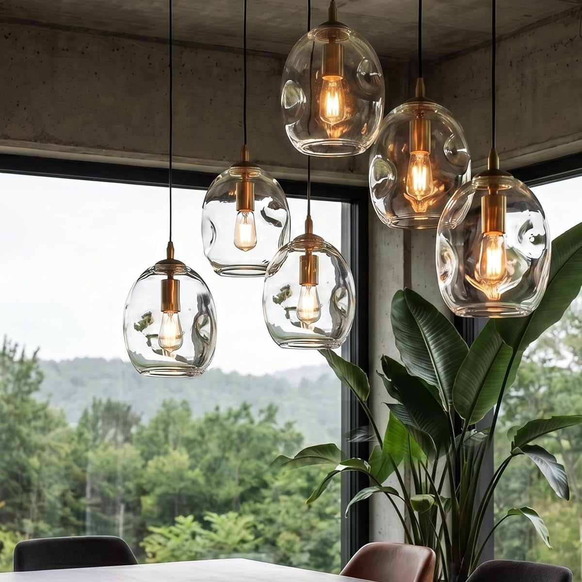 Modern pendant lights hanging above a dining table with a scenic view outside.