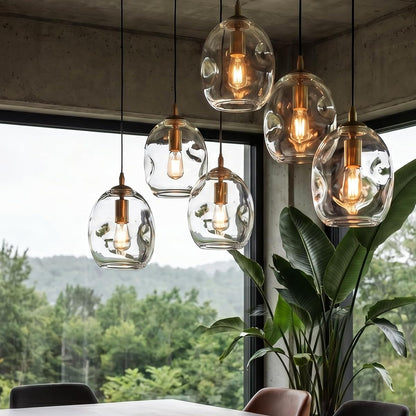 Modern pendant lights hanging above a dining table with a scenic view outside.