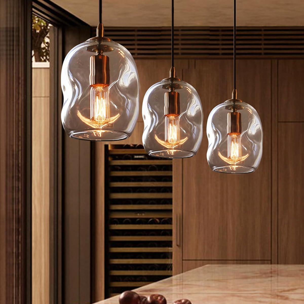 Three pendant lights with glass shades hanging above a dining table.