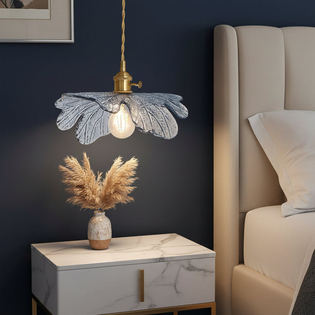 Decorative pendant light with floral design above a small round table in a bedroom setting.