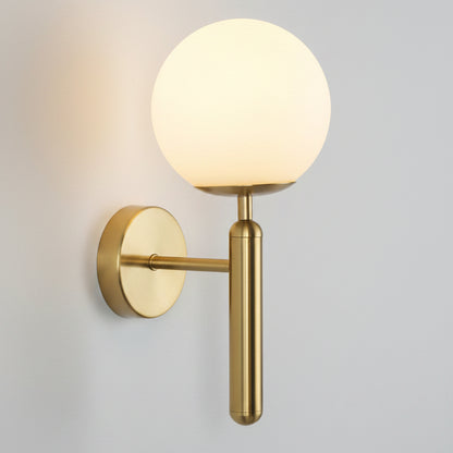 A modern wall-mounted light fixture with a spherical frosted glass globe shade and a brushed brass/gold metal wall plate and vertical stem, shown against a plain white background.