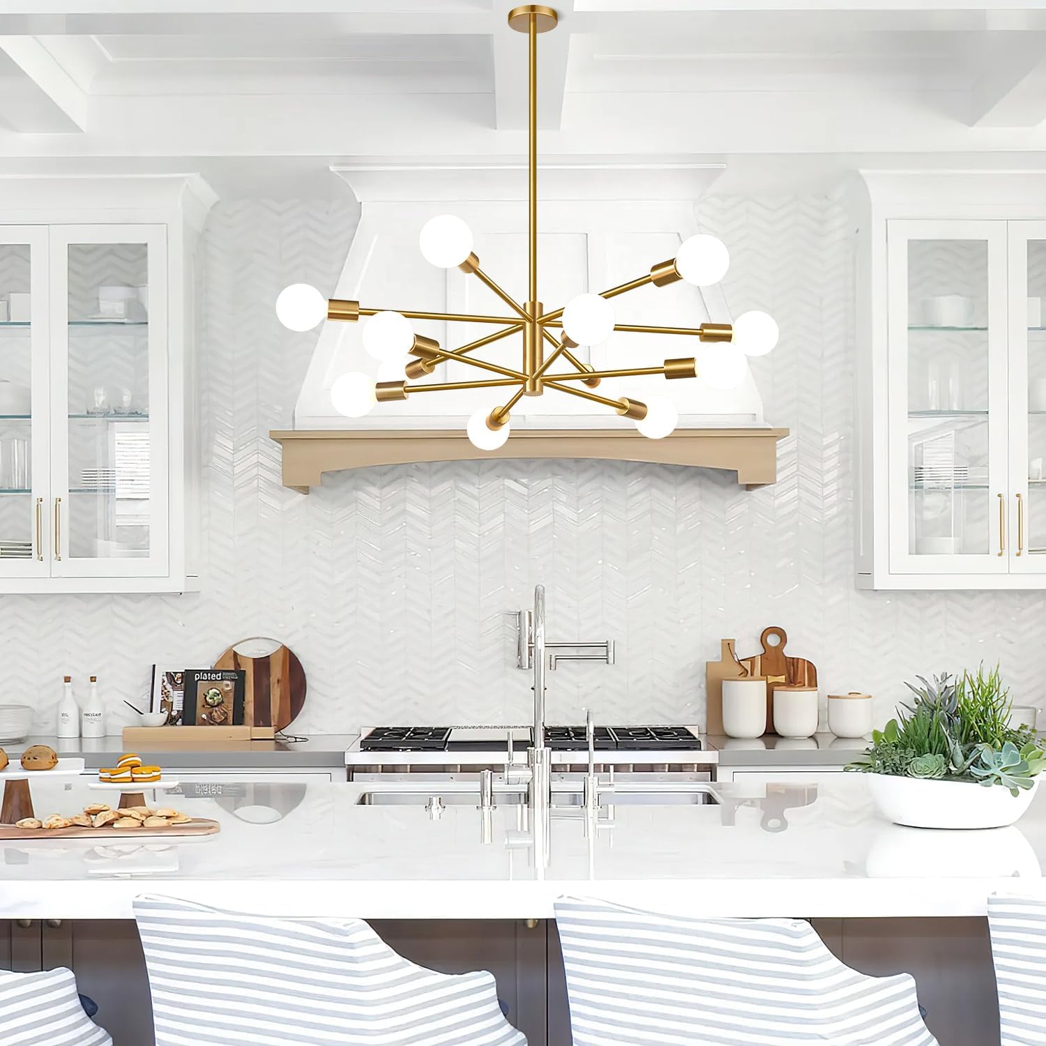Modern kitchen with a gold chandelier, white marble countertops, and stainless steel appliances.