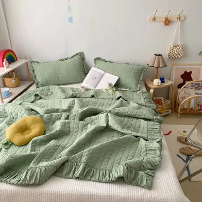Green quilted bedding set on a bed in a room with decor elements.
