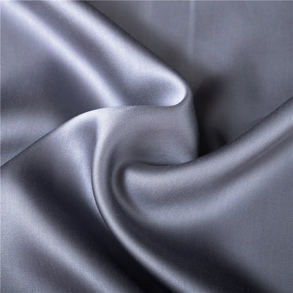 Gray comforter on bed in black-walled bedroom, showcasing Midnight Serenity Silk Duvet Cover.