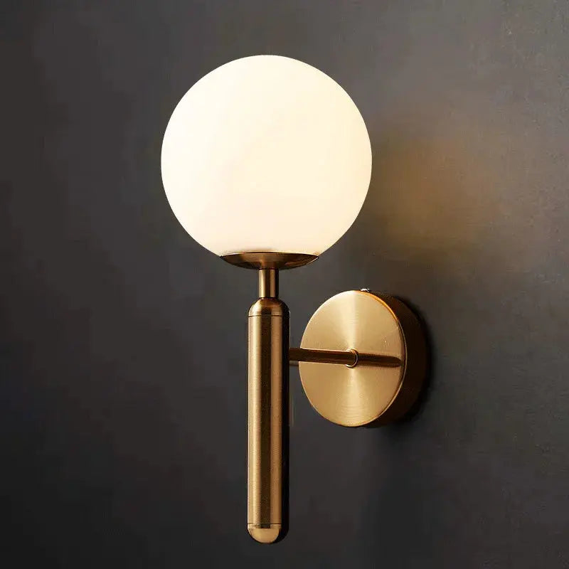 A modern solid brass tubular pole with a clear glass dome wall lamp.