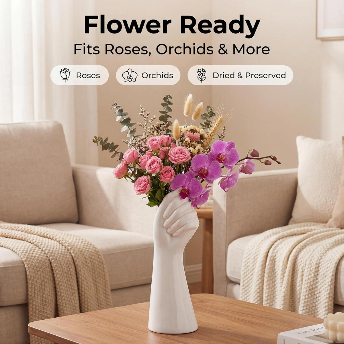 A white sculptural hand-shaped vase filled with pink roses, purple orchids, and dried botanicals on a wooden table in a softly lit living room. Text at the top reads 'Flower Ready' and 'Fits Roses, Orchids & More' with icons for Roses, Orchids, and Dried & Preserved.