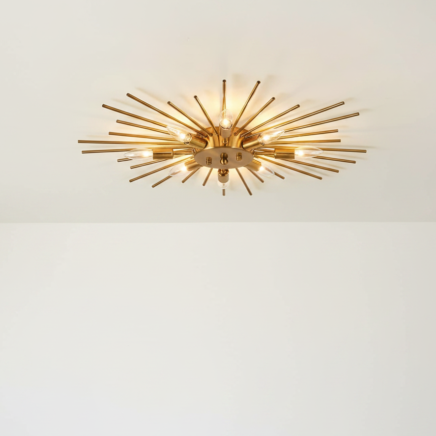 A mid-century modern starburst ceiling light fixture with brass-colored metal rods and warm glowing bulbs, mounted on a white ceiling.