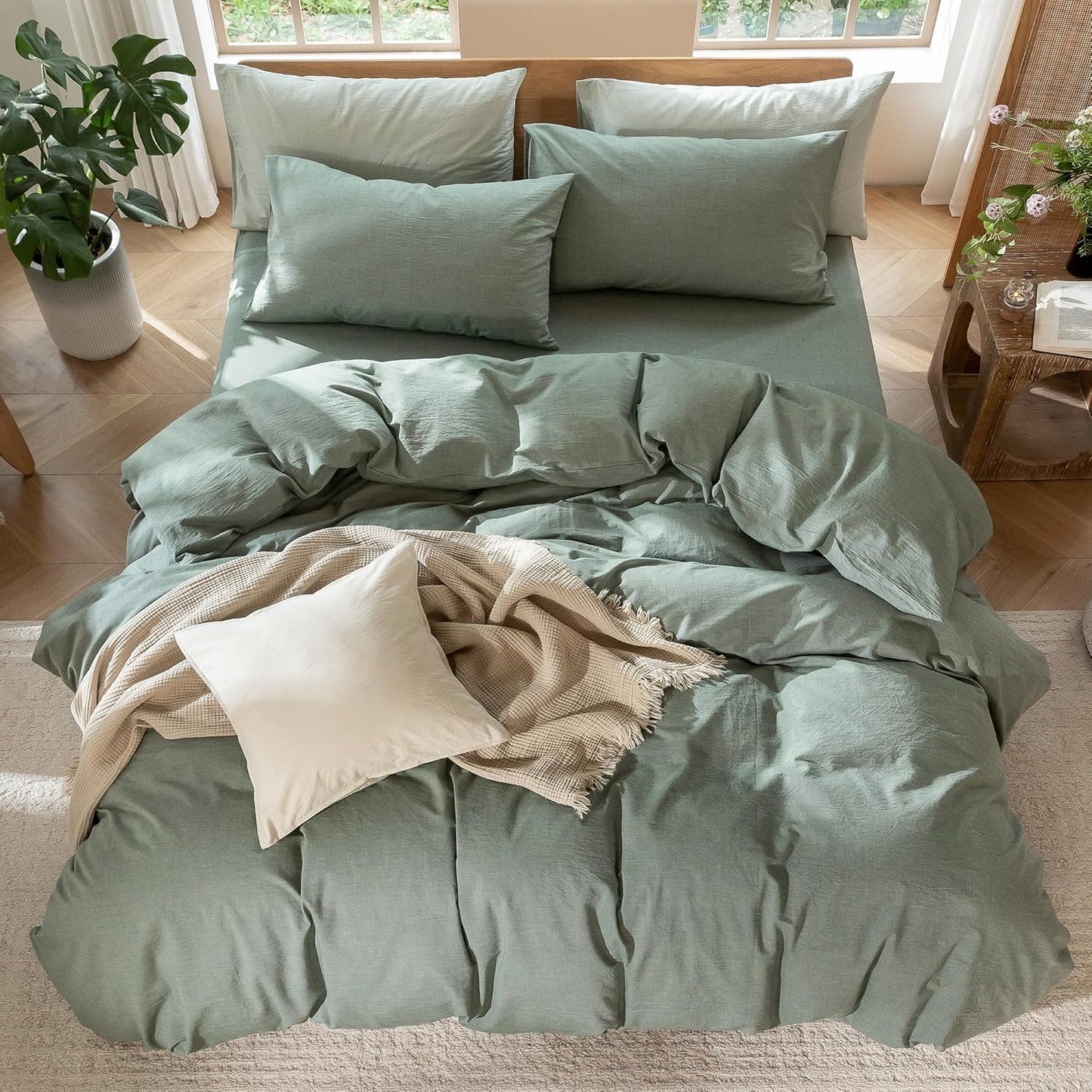 Green bedding set on a bed with pillows and a blanket in a bright room.