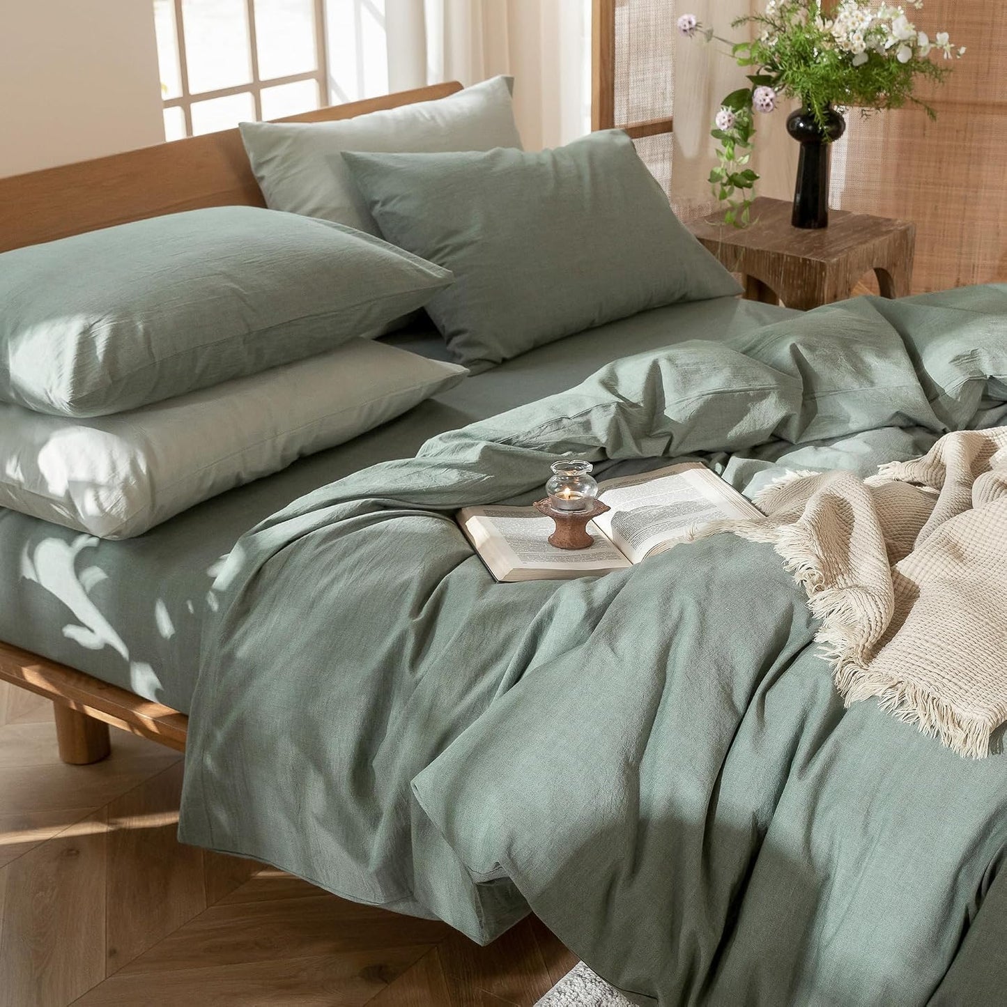 Bed with green bedding and pillows in a bright room
