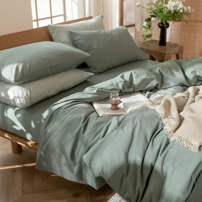 Bed with green bedding and pillows in a bright room