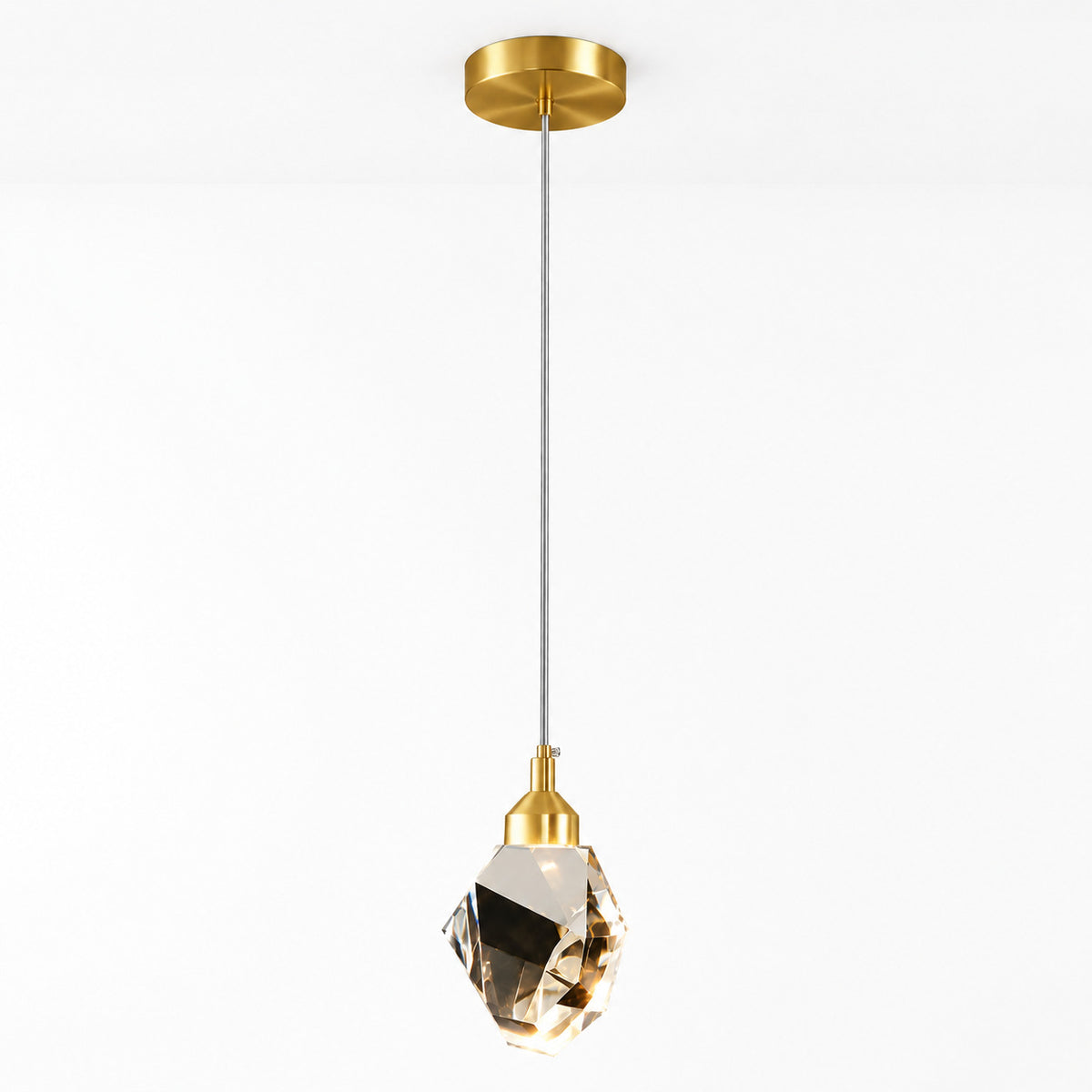 A modern pendant light with a brushed gold ceiling canopy and socket, a slim gray cord, and a faceted clear crystal shade, shown against a plain white background.