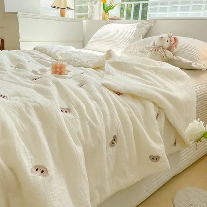 Neatly made bed with white bedding featuring small bear faces, in a bright bedroom.