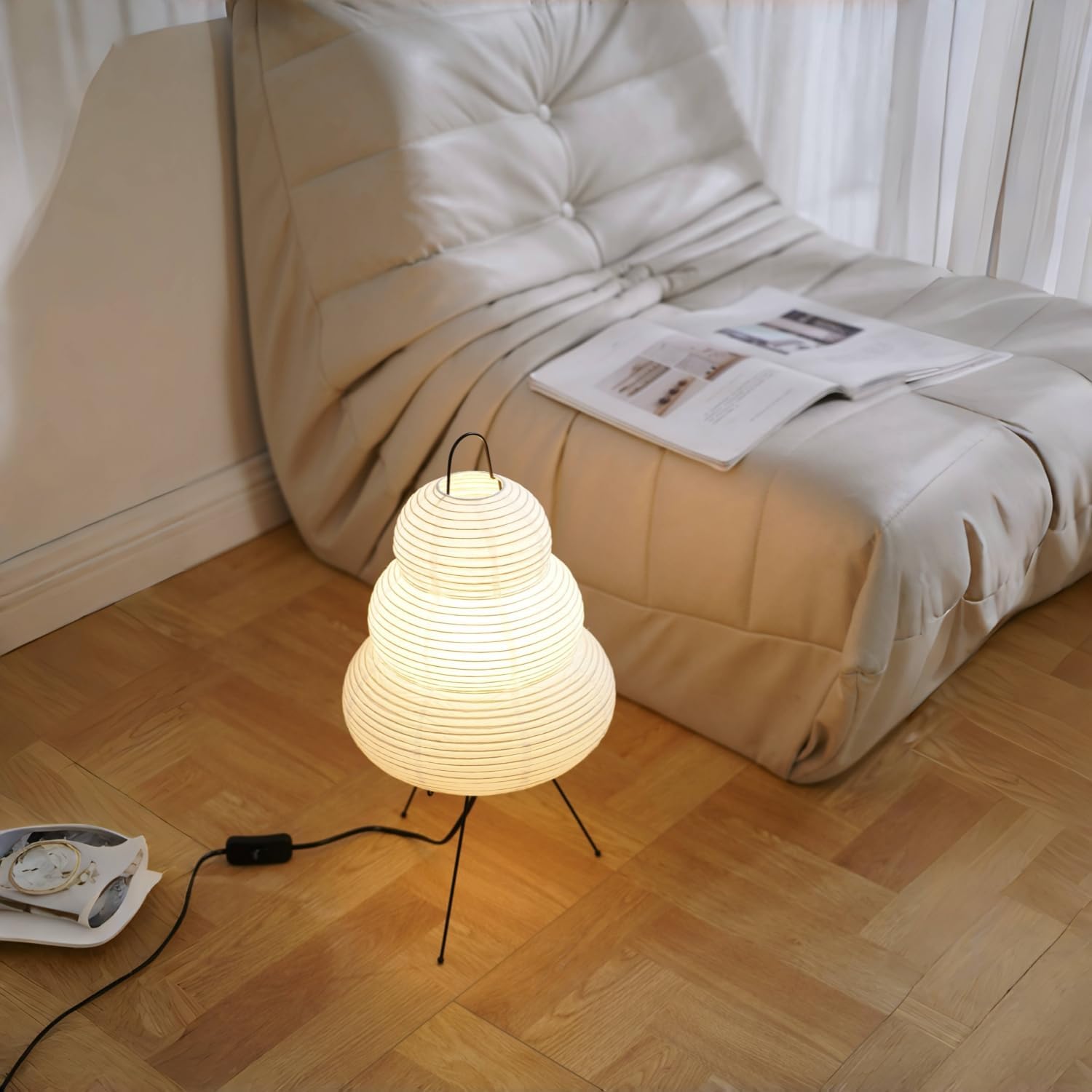 Woven table lamp on a wooden floor with a beige sofa in the background