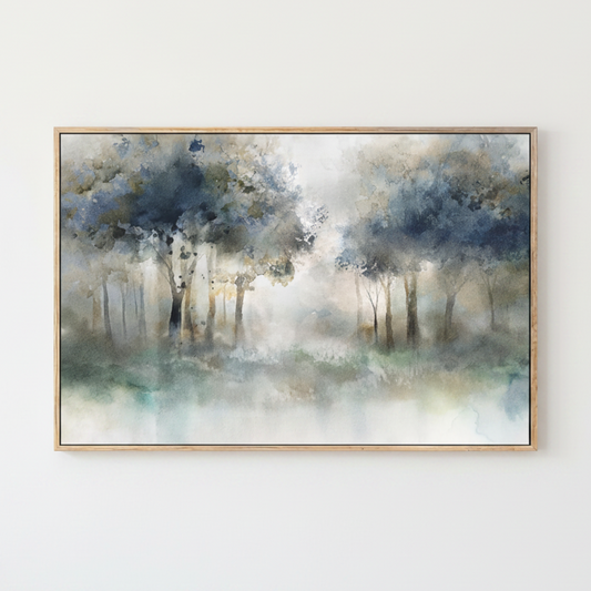 A framed watercolor painting of a misty forest with soft blue, gray, and white tones, hung on a plain white wall.