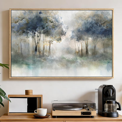 A framed watercolor landscape painting of a misty forest with blue-gray trees and soft green undertones, displayed on a beige wall above a wooden console table with a record player, coffee maker, and cup.