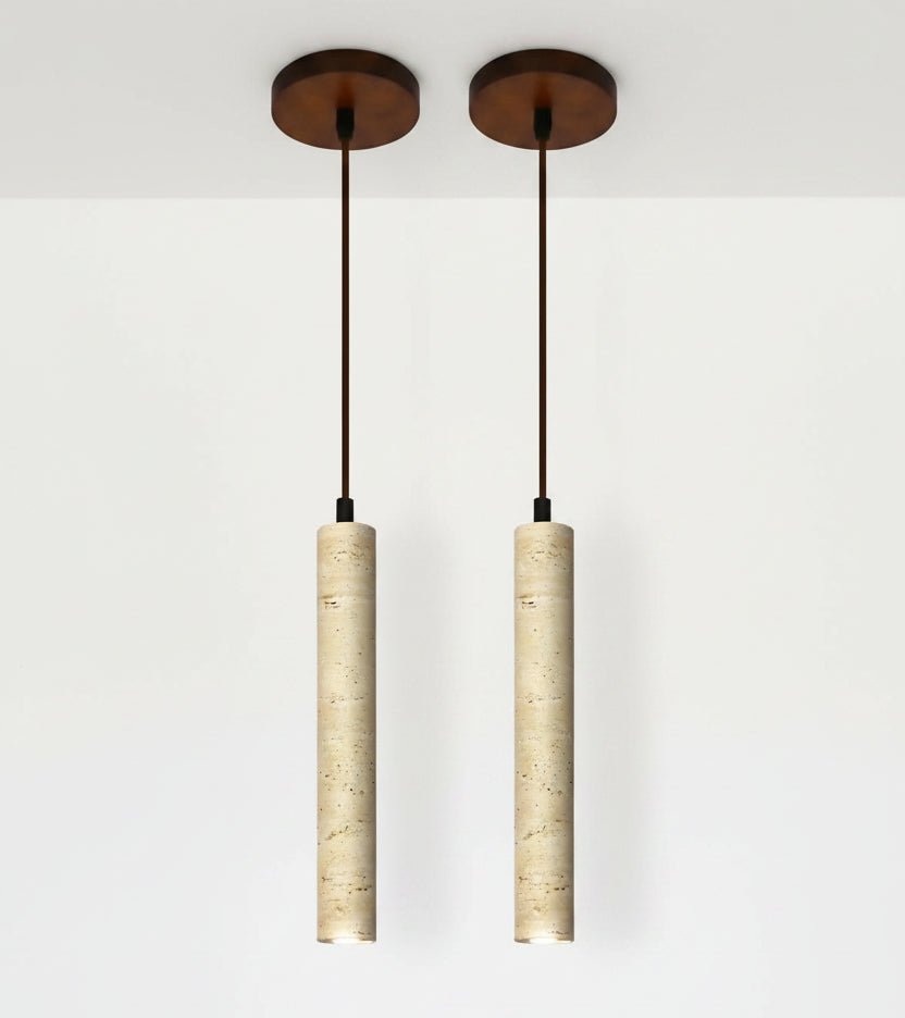 Two pendant lights with cylindrical beige shades and a dining room setting.
