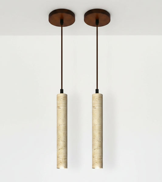 Two pendant lights with cylindrical beige shades and a dining room setting.
