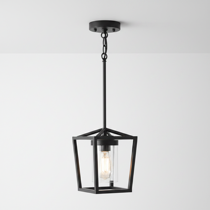 A modern black metal pendant light with a geometric open-frame lantern design and a clear glass shade showing an Edison bulb, set against a plain white background.