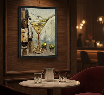 Framed painting of a cocktail on a wall above a table with drinks in a bar setting.