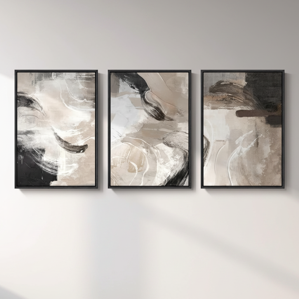 Three framed abstract wall art prints in a row on a light gray wall, featuring black, white, beige, and gray brushstrokes.