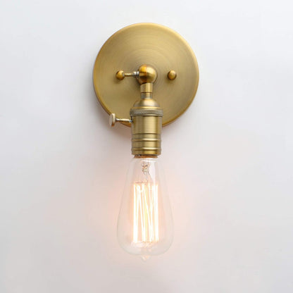 Brass wall sconce with a lit filament bulb on a white background