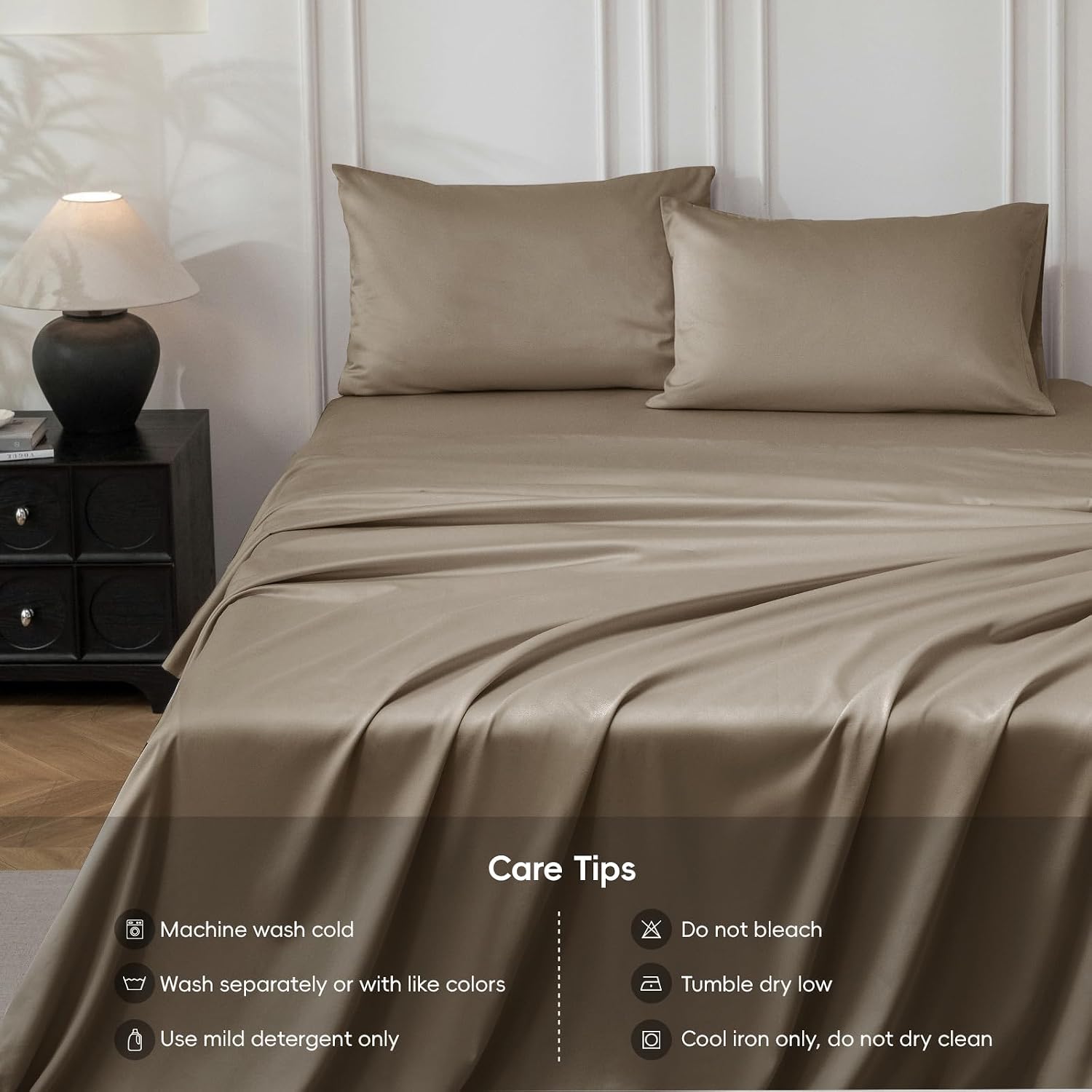A bed made with a smooth, satin-like taupe sheet and two matching pillowcases, shown in a styled bedroom setting with a bedside lamp and a 'Care Tips' text overlay at the bottom.