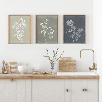 Kitchen with wooden countertop, sink, and framed botanical prints on the wall.