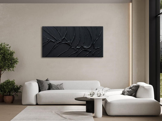 Modern living room with a white sofa, coffee table, and abstract black artwork on the wall.