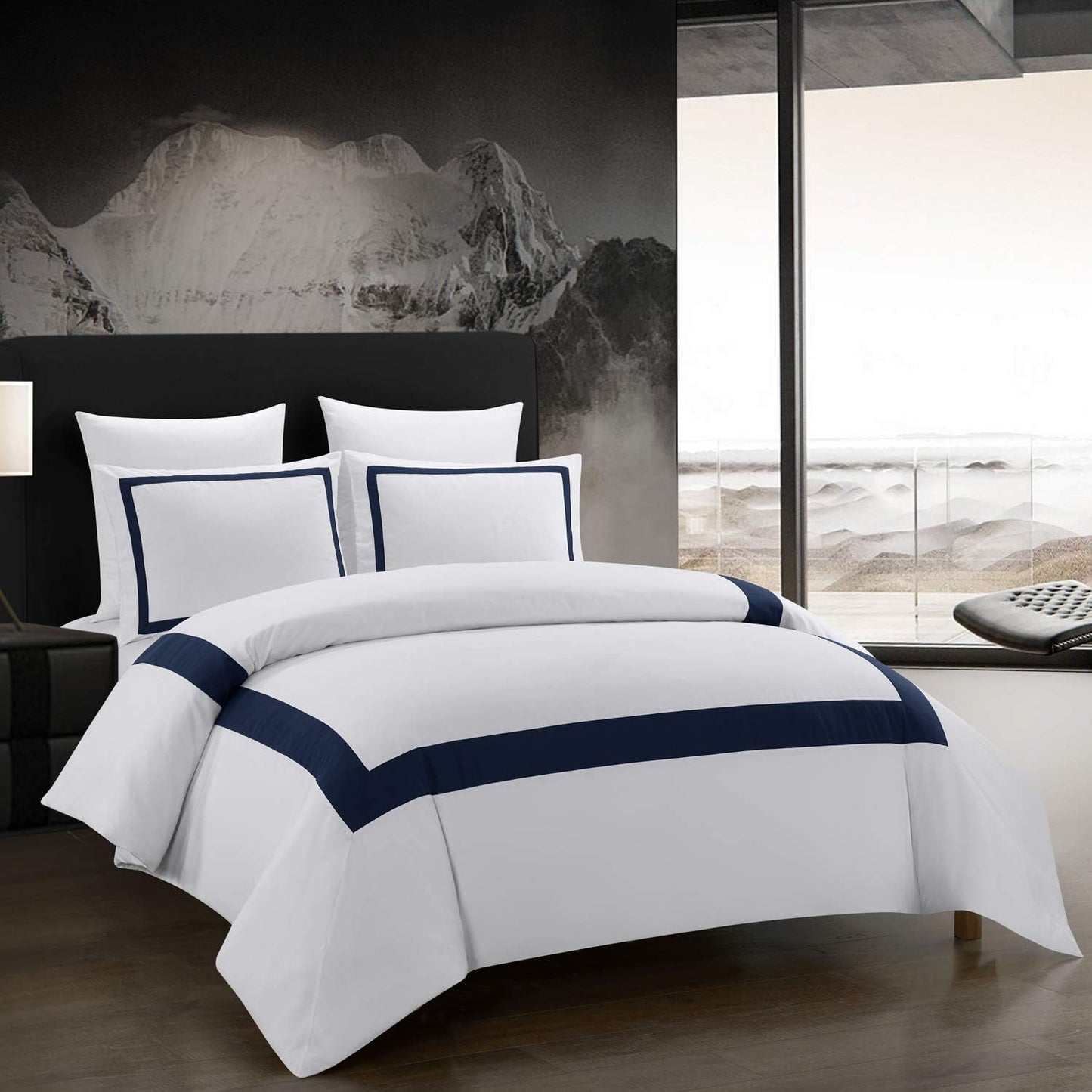 White bedding set with navy trim on a bed in a modern bedroom.