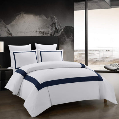 White bedding set with navy trim on a bed in a modern bedroom.