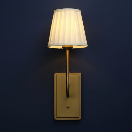Wall-mounted lamp with a white shade and gold fixture on a light gray background