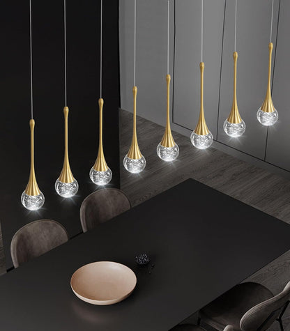Modern pendant lights hanging above a dining table in a darkly decorated room.