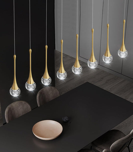 Modern pendant lights hanging above a dining table in a darkly decorated room.