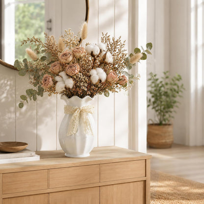 Decorative flower arrangement in a white vase on a wooden cabinet with a blurred indoor background