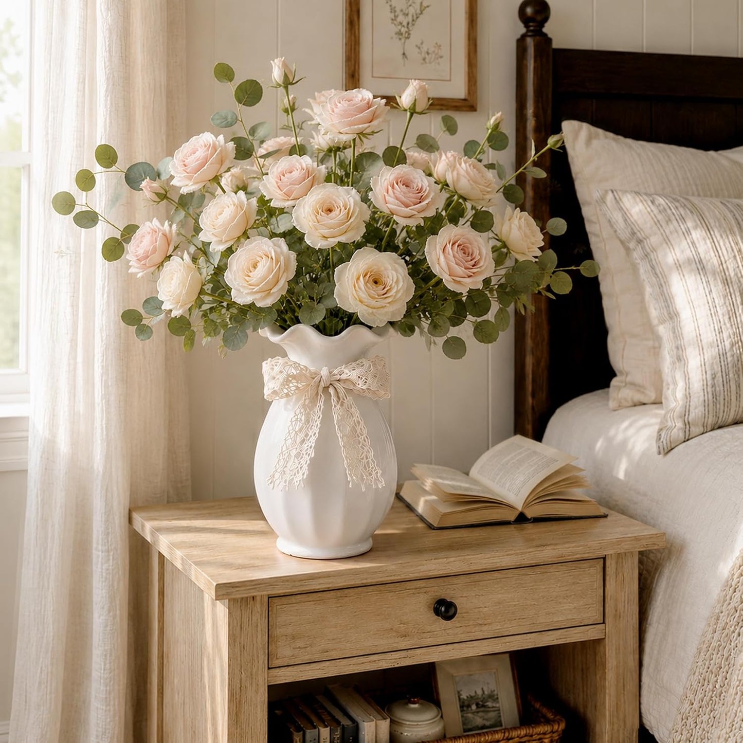 Floral arrangement in a white vase on a wooden nightstand next to a bed.