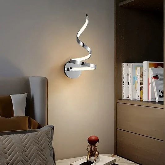 Modern minimalist spiral LED wall sconce with a wedge base, shining a soft light into a room with a beige sofa and pillows, with a contemporary painting in the background.