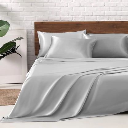 CloudSatin Dream Bed Sheet Set showcased on a bed alongside silver grey pillows and a plant.