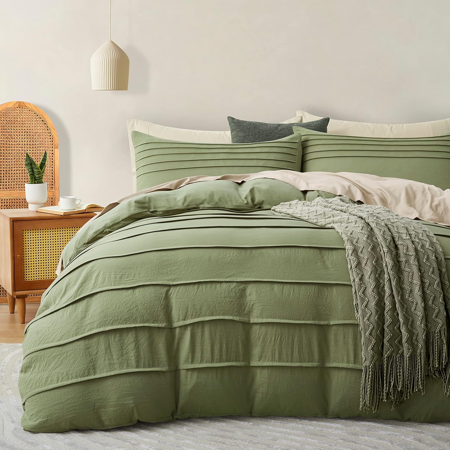 Green bedding set on a bed in a bedroom with a side table and lamp.