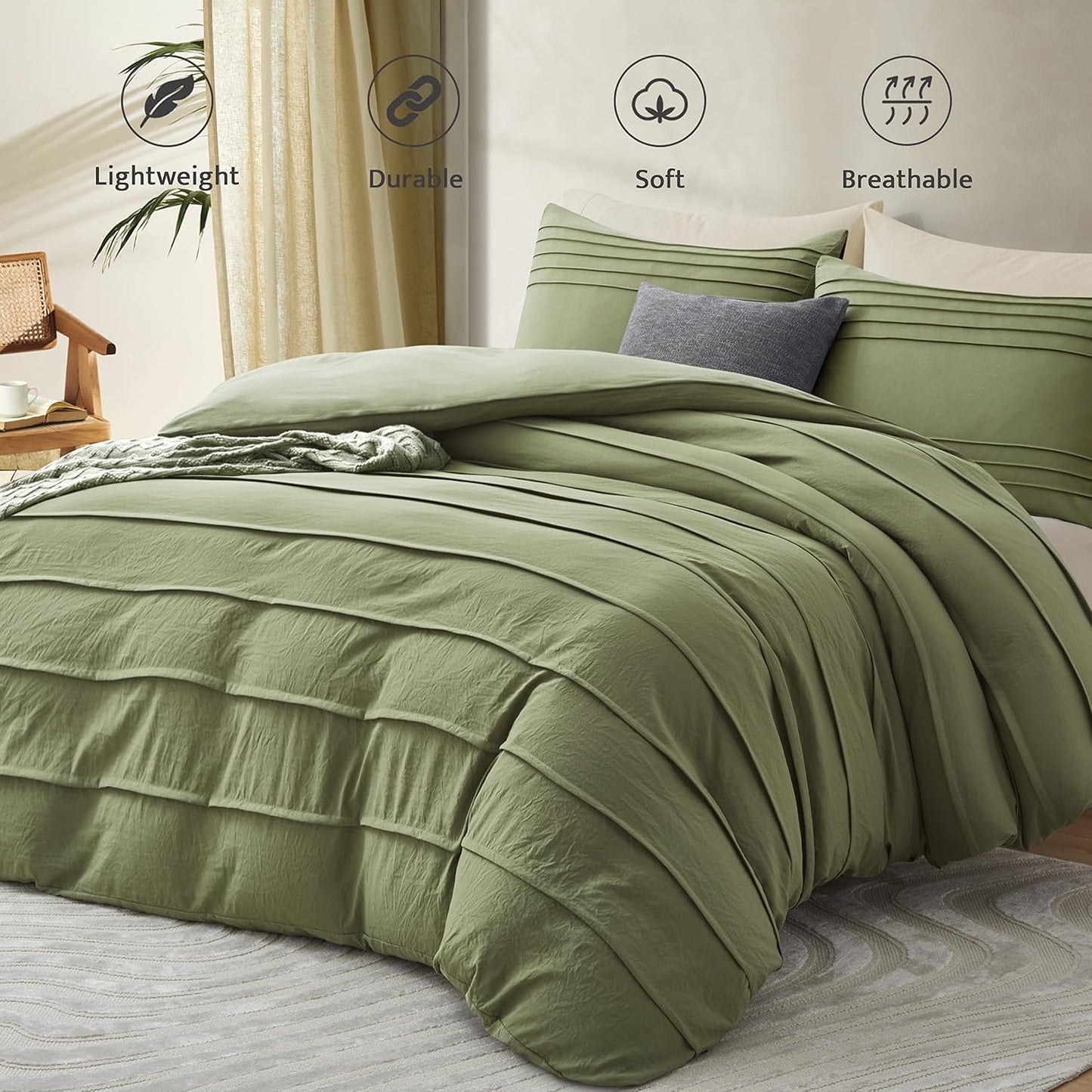 An olive green pleated bedding set on a bed, featuring a duvet cover and matching pillow shams with a small gray accent pillow. The background shows a softly lit bedroom with beige curtains, a wooden chair, and decorative icons highlighting product features: Lightweight, Durable, Soft, and Breathable.