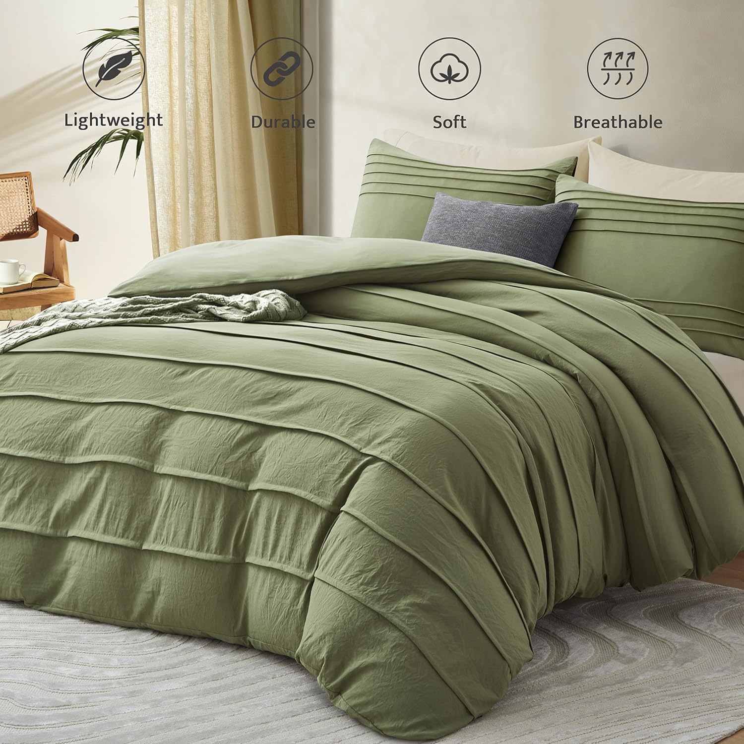 An olive green pleated bedding set on a bed, featuring a duvet cover and matching pillow shams with a small gray accent pillow. The background shows a softly lit bedroom with beige curtains, a wooden chair, and decorative icons highlighting product features: Lightweight, Durable, Soft, and Breathable.