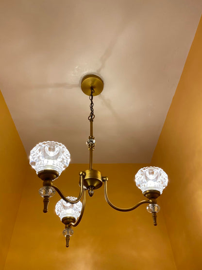 Vintage-style chandelier with glass shades hanging from a ceiling.