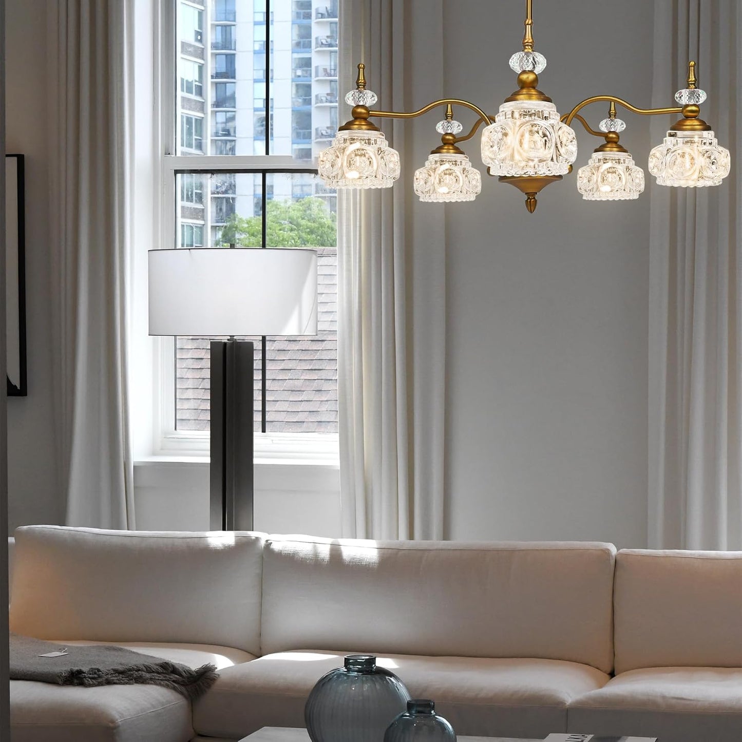 Modern living room with a chandelier, sofa, and lamp.