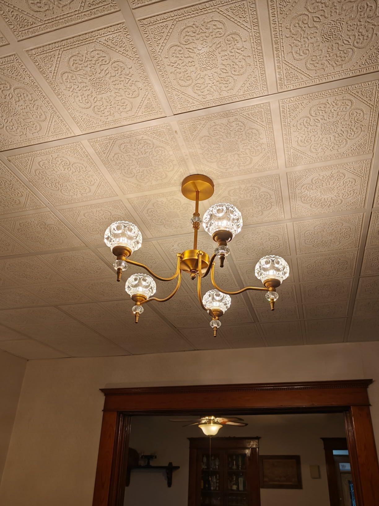 Gold chandelier with clear glass shades on a decorative ceiling