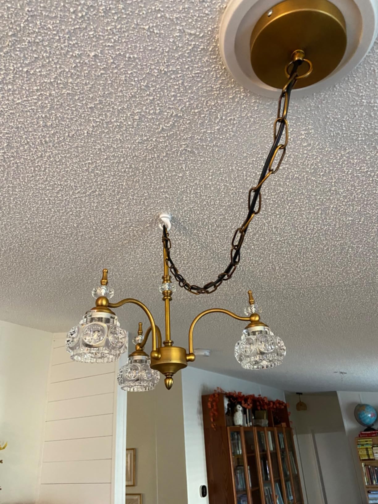 Gold chandelier with crystal glass shades hanging from a ceiling.