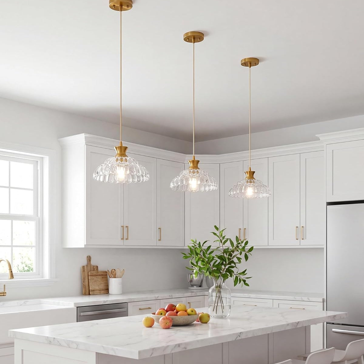 Three Mgcanyu glass pendant lights with gold-finished canopies and cords hang over a white kitchen island in a bright, modern kitchen. The text 'Kitchen Island' and 'Mgcanyu Glass Pendant Light' is overlaid at the bottom.