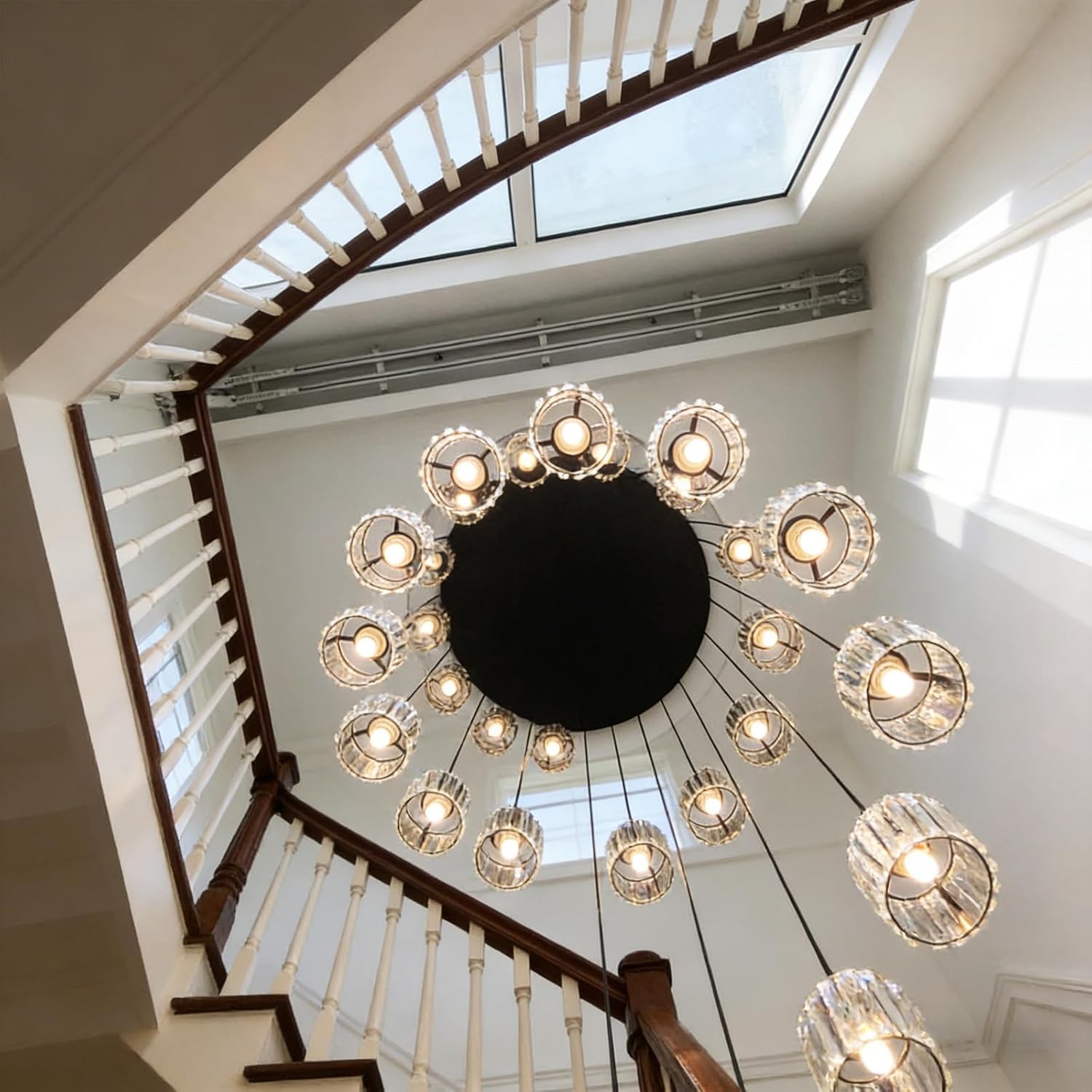 Chandelier hanging from a ceiling in a home with a staircase and skylight.