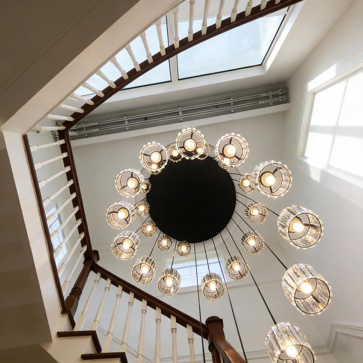 Chandelier hanging from a ceiling in a home with a staircase and skylight.