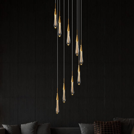 Modern pendant light fixture hanging against a dark wall with a sofa in the foreground.